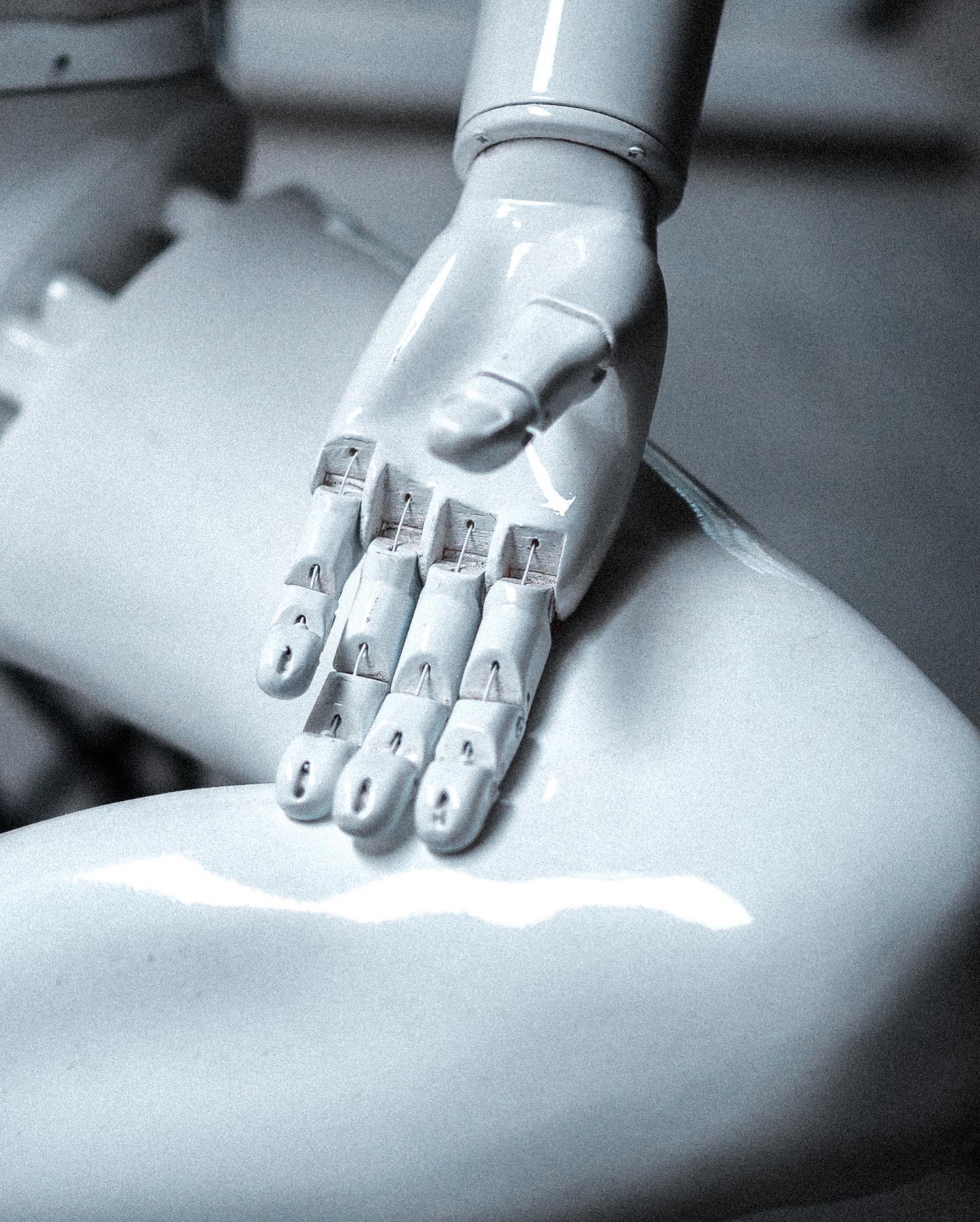 An articulated hand resting on the sculpture's leg